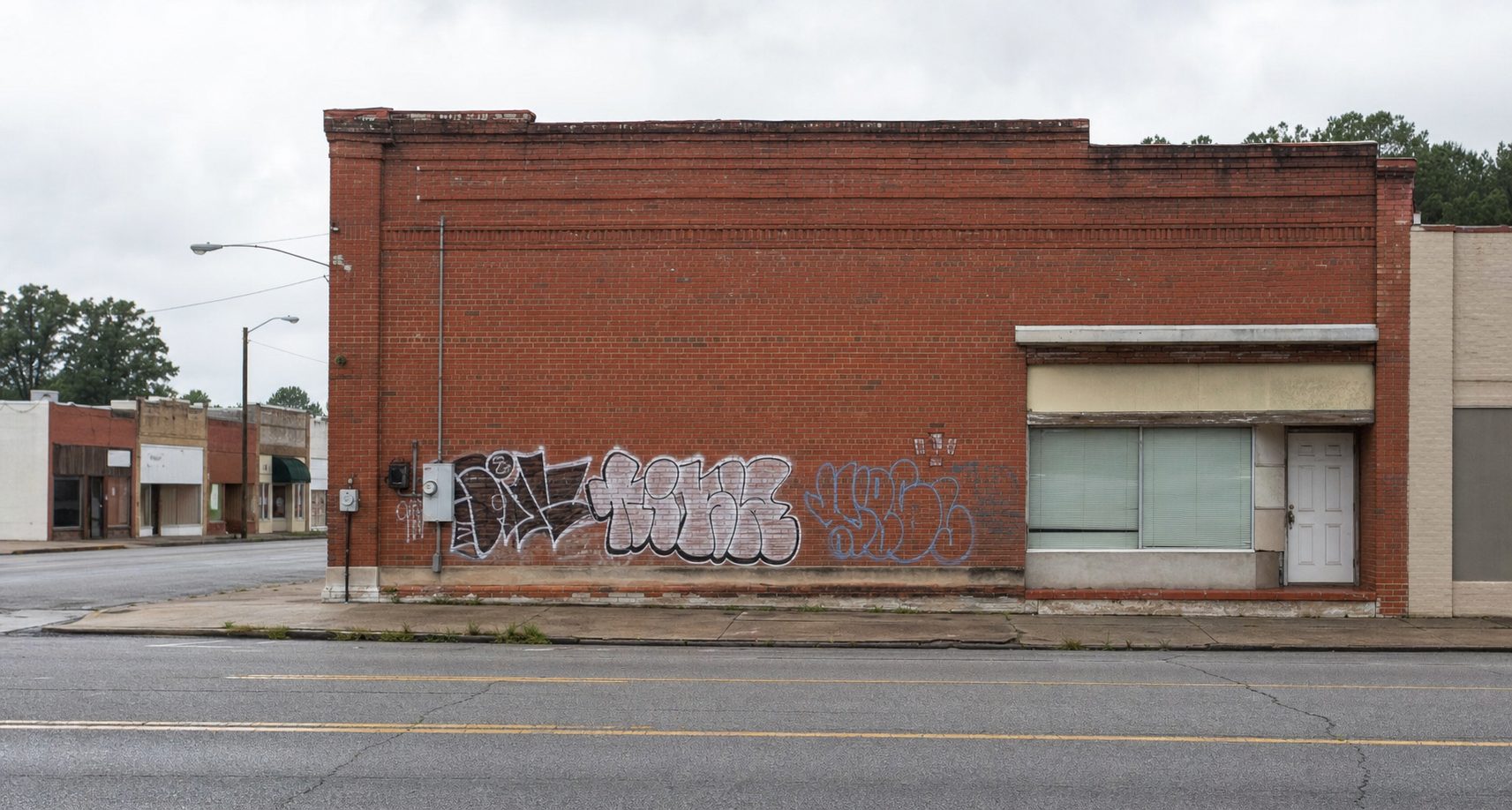 Restoration crew power-washing graffiti from commercial brick wall